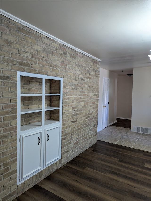 unfurnished room with dark hardwood / wood-style flooring and brick wall