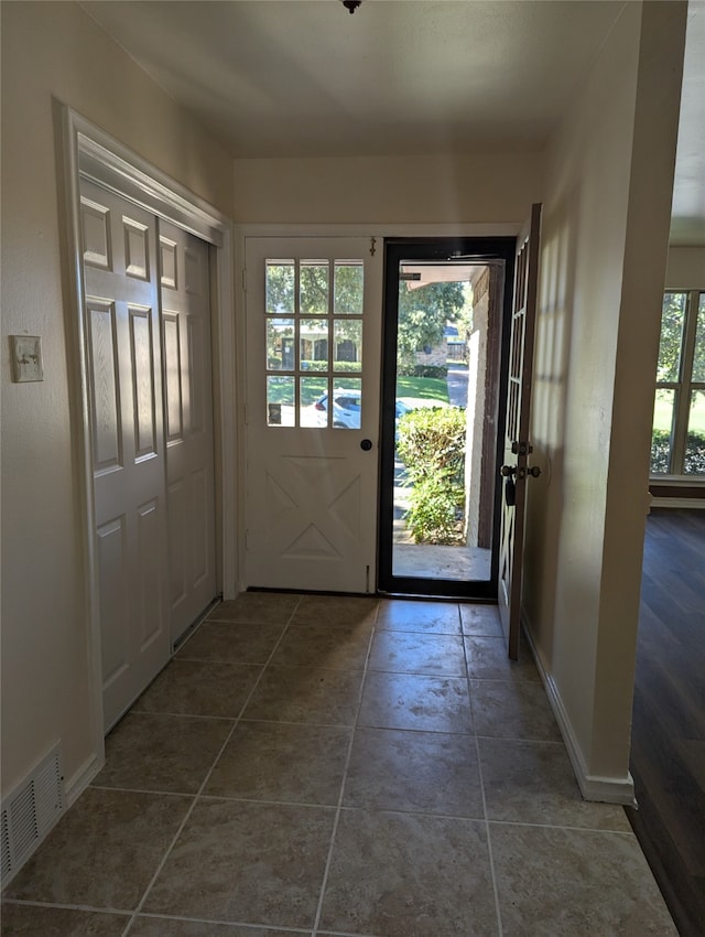 entryway with dark tile patterned floors