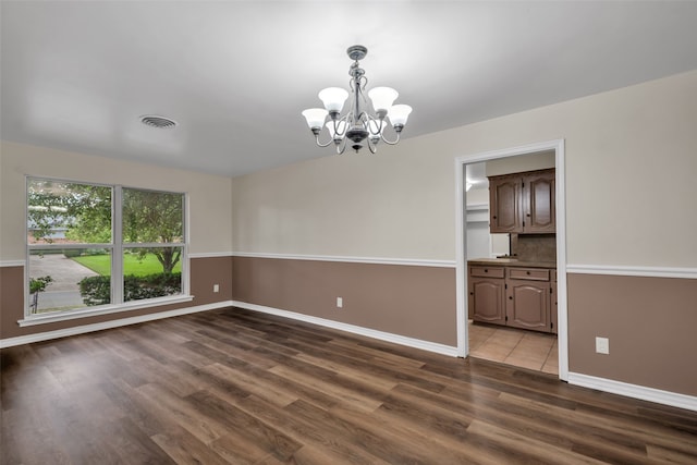 unfurnished room featuring a notable chandelier and dark hardwood / wood-style floors