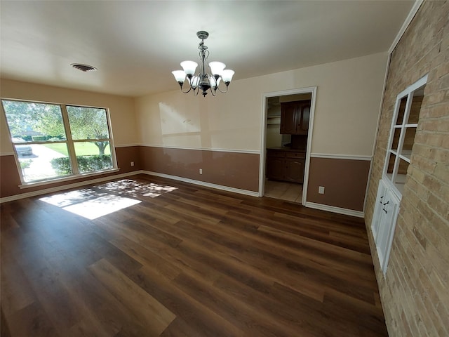 unfurnished dining area featuring a chandelier and dark hardwood / wood-style floors