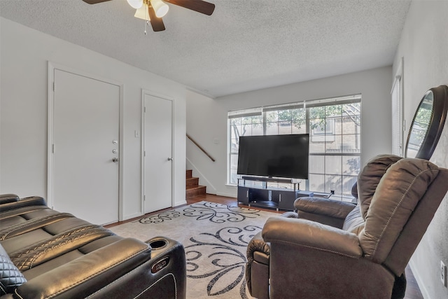 living room with a textured ceiling, ceiling fan, and light hardwood / wood-style flooring