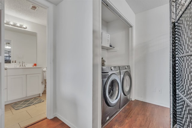 laundry area with a textured ceiling, dark hardwood / wood-style floors, separate washer and dryer, and sink