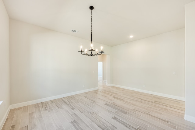 spare room featuring light hardwood / wood-style flooring and a notable chandelier