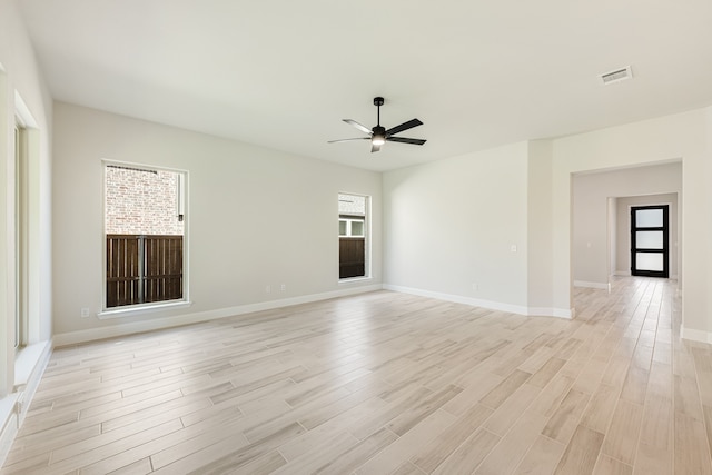 spare room with light wood-type flooring, a wealth of natural light, and ceiling fan