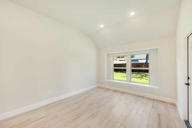 spare room with light wood-type flooring and lofted ceiling