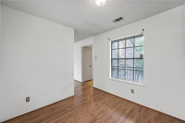 spare room with wood-type flooring and a textured ceiling