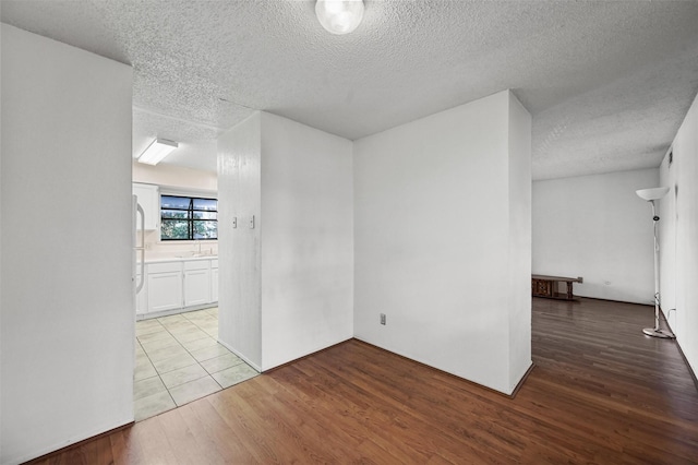 empty room featuring a textured ceiling, light hardwood / wood-style floors, and sink