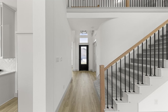 entryway with a towering ceiling and light wood-type flooring