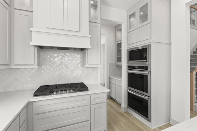 kitchen featuring tasteful backsplash, white cabinetry, light hardwood / wood-style floors, and stainless steel appliances