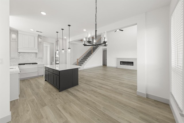 kitchen with pendant lighting, black gas cooktop, tasteful backsplash, white cabinets, and a kitchen island