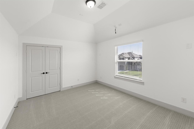 interior space featuring a closet, lofted ceiling, and light carpet