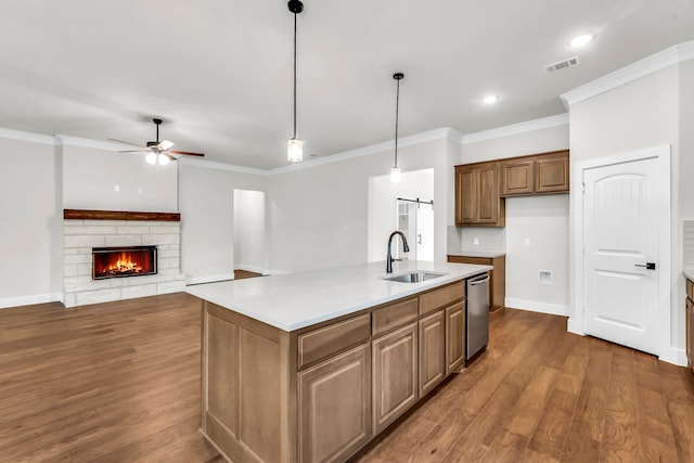 kitchen featuring hanging light fixtures, a barn door, sink, a kitchen island with sink, and stainless steel dishwasher