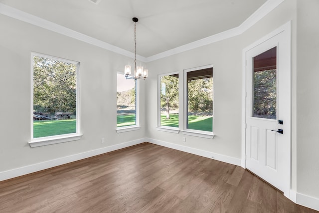 unfurnished dining area featuring dark hardwood / wood-style flooring, a notable chandelier, a healthy amount of sunlight, and crown molding