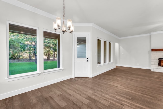 unfurnished dining area with a fireplace, dark hardwood / wood-style floors, a chandelier, and ornamental molding