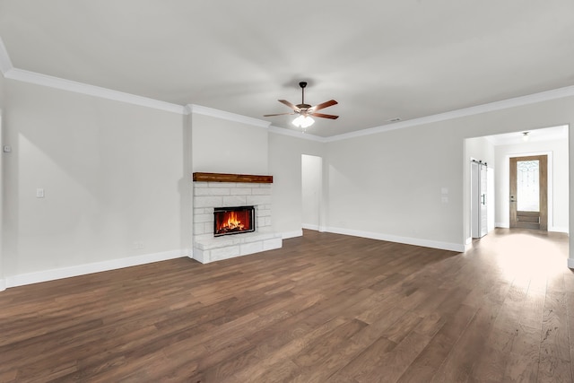 unfurnished living room with dark hardwood / wood-style flooring, a stone fireplace, ceiling fan, and crown molding