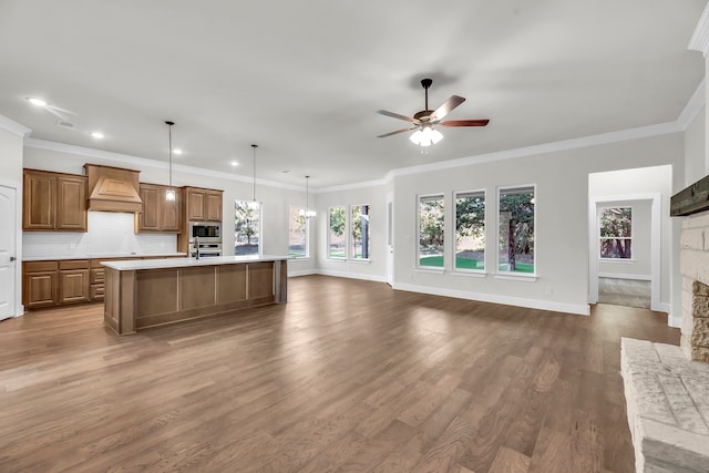 kitchen featuring hardwood / wood-style floors, a center island with sink, pendant lighting, and crown molding