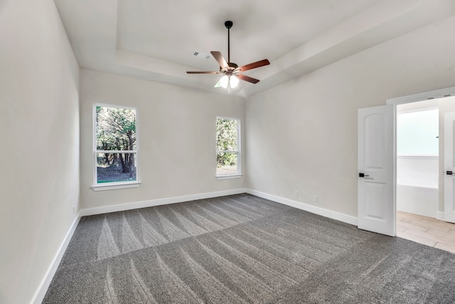 carpeted empty room featuring ceiling fan and a tray ceiling