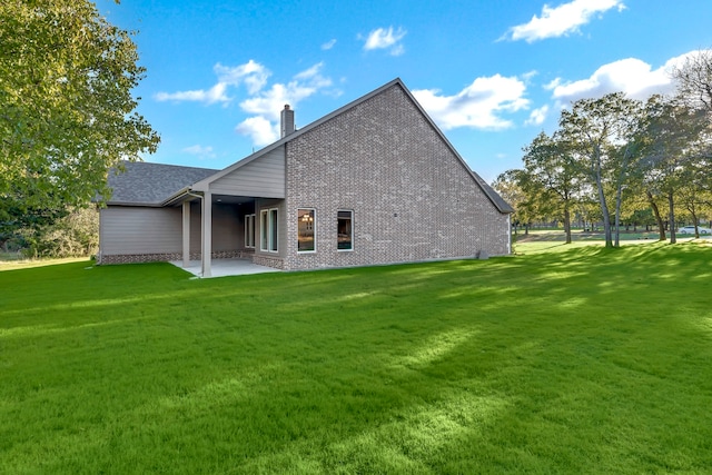 rear view of house with a lawn and a patio