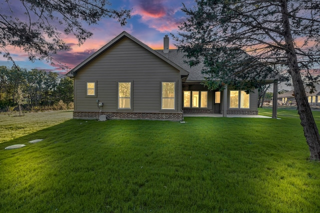 back house at dusk featuring a yard