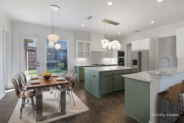 kitchen with stainless steel appliances, white cabinets, hanging light fixtures, backsplash, and a kitchen island