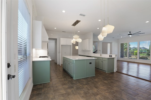 kitchen featuring white cabinets, dark hardwood / wood-style flooring, a kitchen island, ceiling fan, and decorative light fixtures