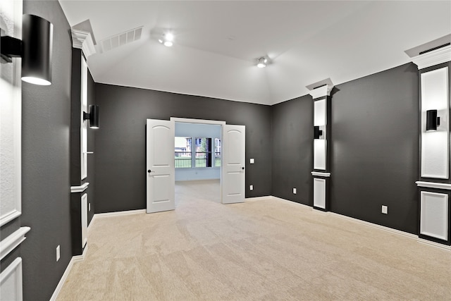 carpeted home theater room with decorative columns and vaulted ceiling