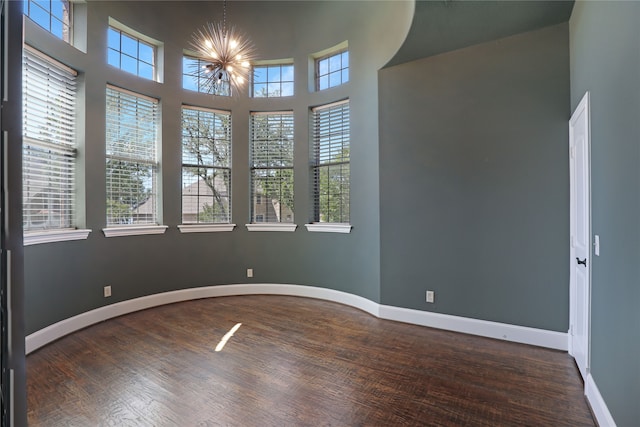 unfurnished room featuring an inviting chandelier, dark hardwood / wood-style floors, and a healthy amount of sunlight