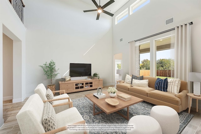 living room featuring light hardwood / wood-style flooring, ceiling fan, and a high ceiling