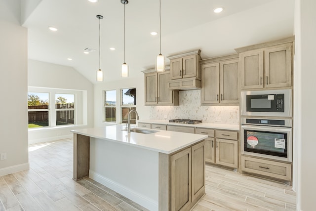 kitchen featuring appliances with stainless steel finishes, pendant lighting, sink, lofted ceiling, and a kitchen island with sink