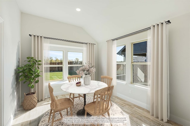 dining area featuring vaulted ceiling and light hardwood / wood-style floors