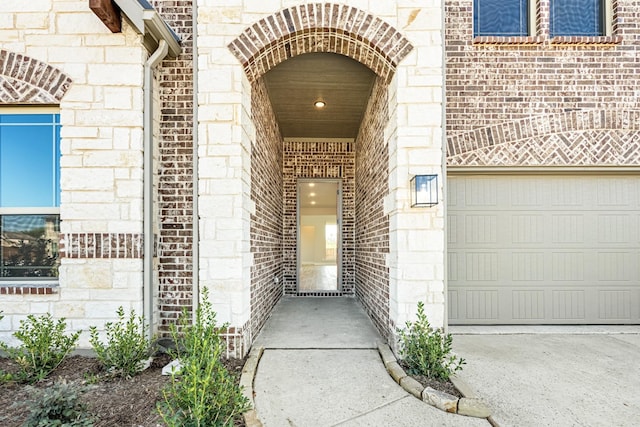 property entrance featuring stone siding, brick siding, and a garage