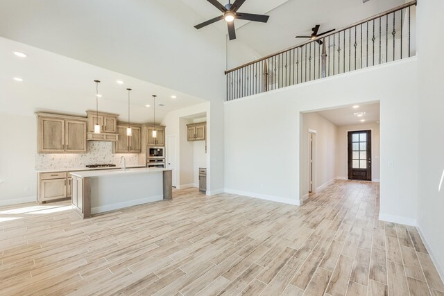 kitchen with ceiling fan, light countertops, open floor plan, built in microwave, and light wood-style floors
