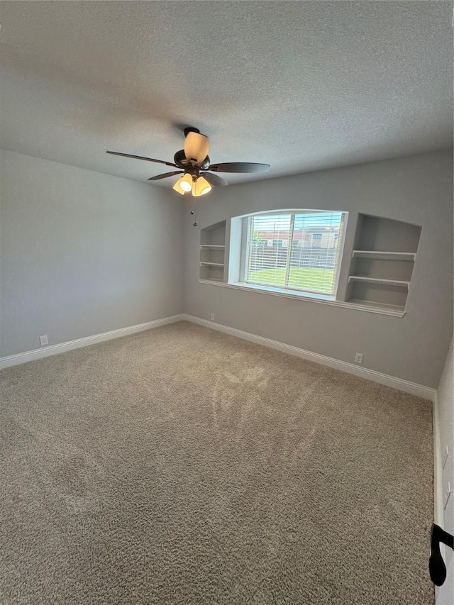 spare room with carpet, a textured ceiling, built in features, and ceiling fan