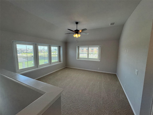 carpeted spare room with ceiling fan, a healthy amount of sunlight, and lofted ceiling