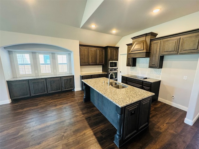 kitchen with built in microwave, backsplash, an island with sink, lofted ceiling, and black electric cooktop