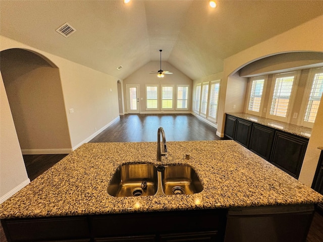 kitchen featuring light stone countertops and a center island with sink