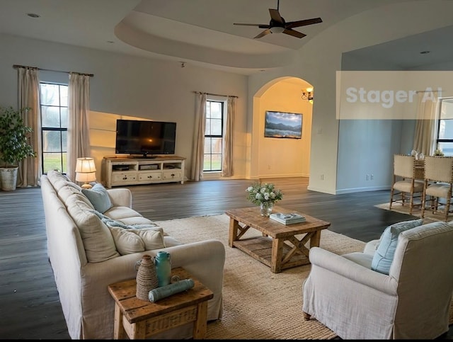 living room featuring wood-type flooring, a raised ceiling, and ceiling fan