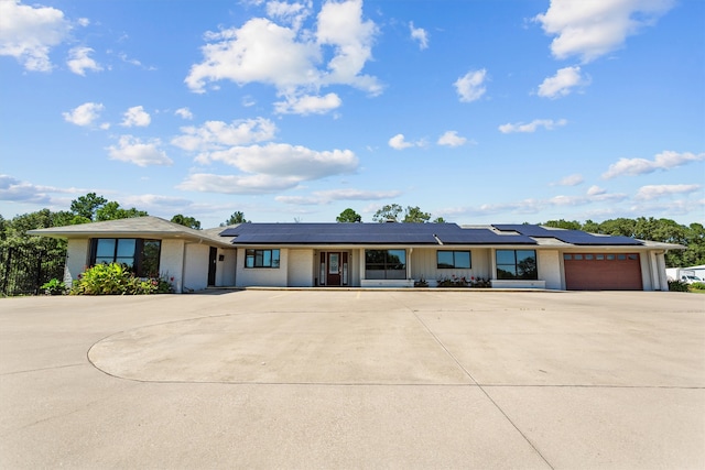 ranch-style house with a garage and solar panels