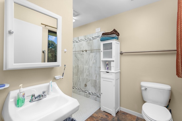 bathroom featuring tile patterned floors, toilet, sink, and a tile shower