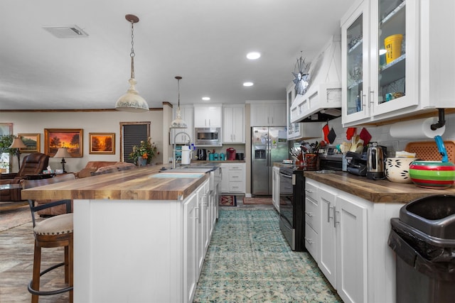 kitchen featuring white cabinets, stainless steel appliances, sink, and butcher block counters