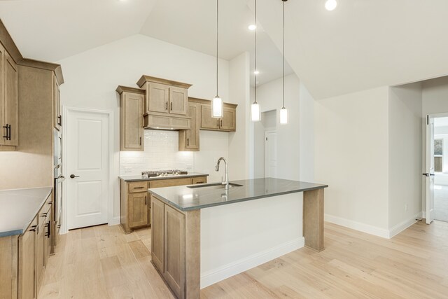 kitchen featuring tasteful backsplash, a center island with sink, pendant lighting, light hardwood / wood-style floors, and sink