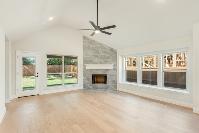 unfurnished living room featuring light hardwood / wood-style flooring, a tiled fireplace, high vaulted ceiling, and ceiling fan