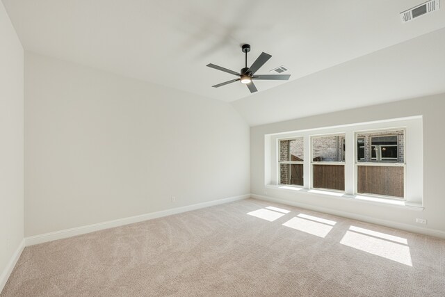 carpeted spare room with ceiling fan and vaulted ceiling