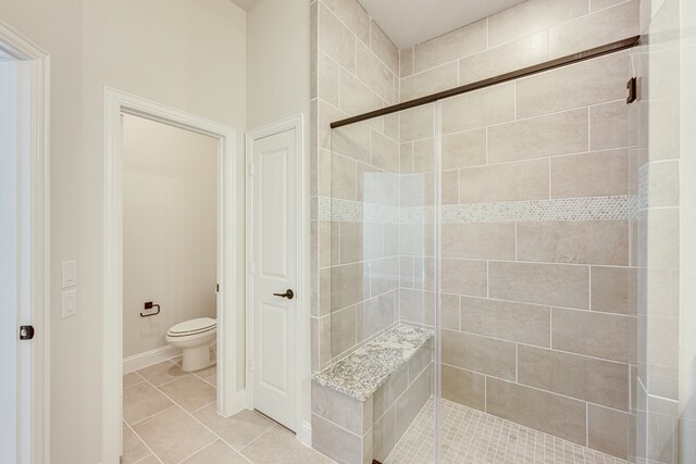 bathroom featuring toilet, walk in shower, and tile patterned flooring