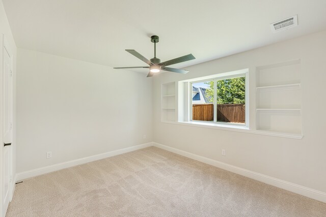 carpeted empty room featuring built in features and ceiling fan