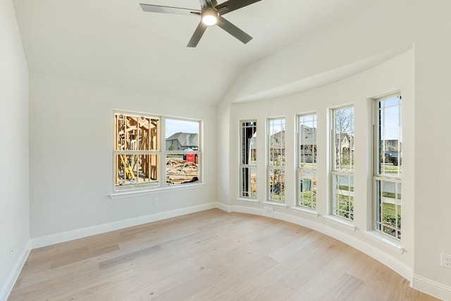 spare room featuring light wood finished floors, lofted ceiling, baseboards, and ceiling fan