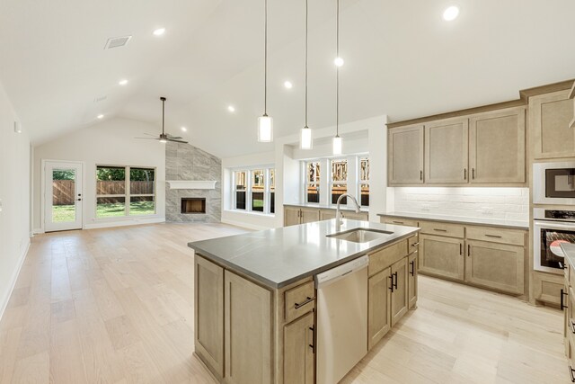 kitchen with sink, an island with sink, a high end fireplace, stainless steel appliances, and lofted ceiling