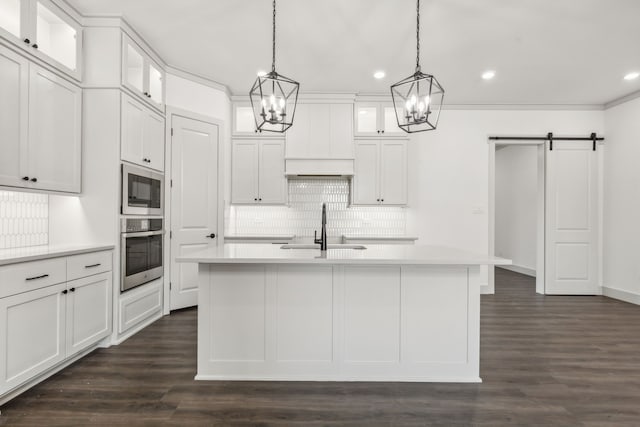 kitchen featuring an island with sink, a barn door, sink, and stainless steel oven