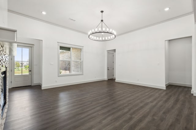 unfurnished living room with crown molding, dark hardwood / wood-style floors, a chandelier, and a stone fireplace