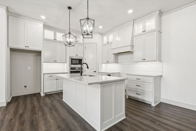 kitchen featuring sink, white cabinetry, an island with sink, built in microwave, and stainless steel oven